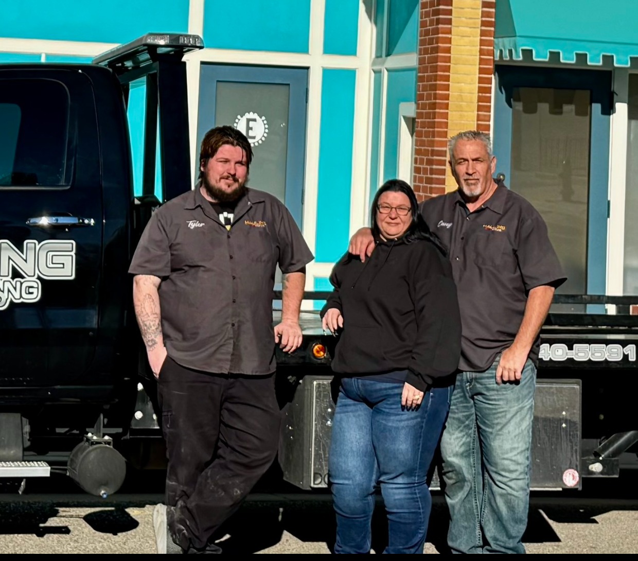 Tyler, Kelly and Casey Nielsen of Hauling Ace Towing in front of the truck